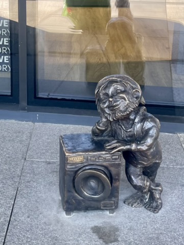 A bronze Wrocław gnome beside a washing machine